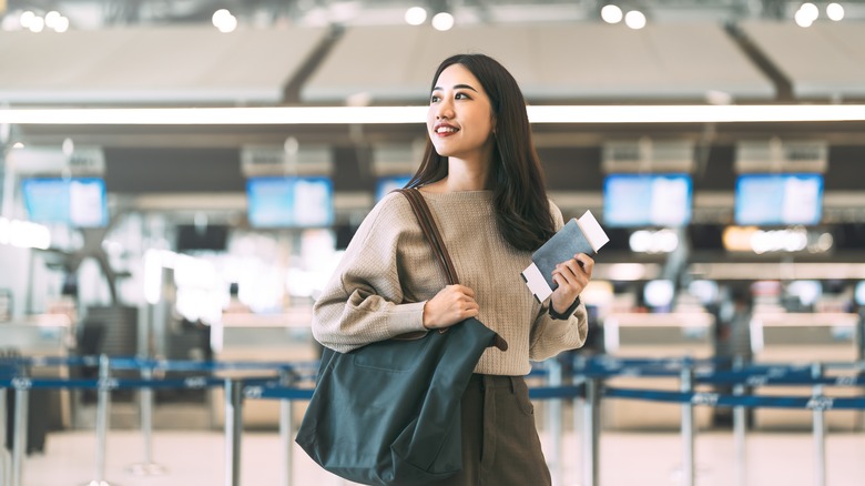 woman in airport holding shoulder bag