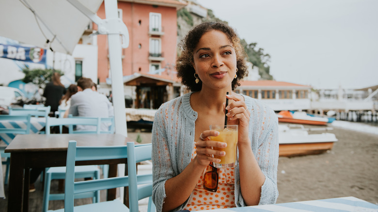 Woman drinking iced coffee on the beach