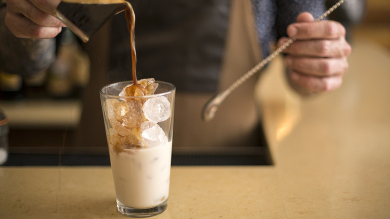 Barista pouring espreso shot over iced drink