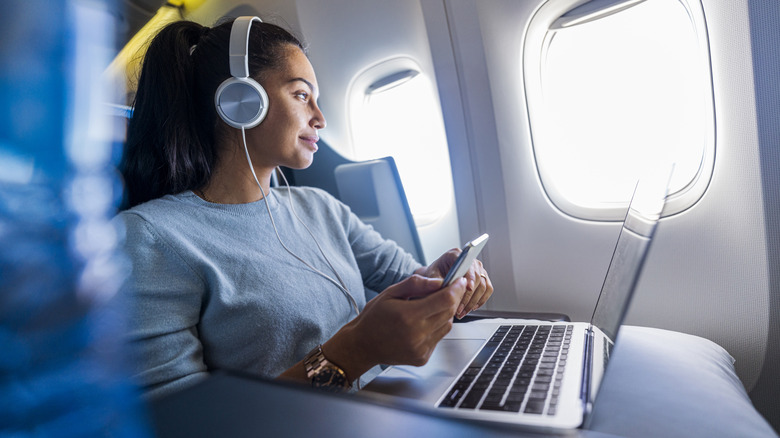 A woman using a laptop on a plane.