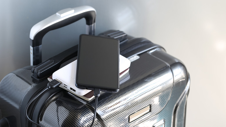 A suitcase with a phone and power bank on top.
