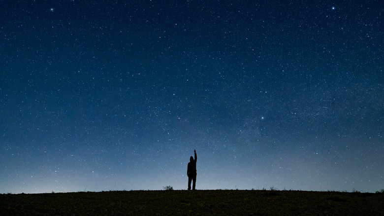 Aerial-view sillhouette of a man in a field surrounded by stars