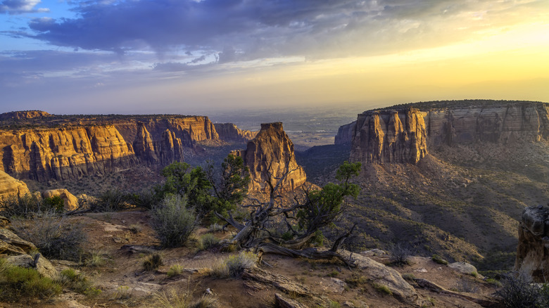 Canyons and rock formations with a sun setting and cloudy skies