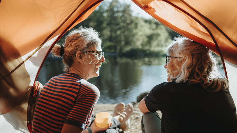 two women smiling at each other in a tent by river