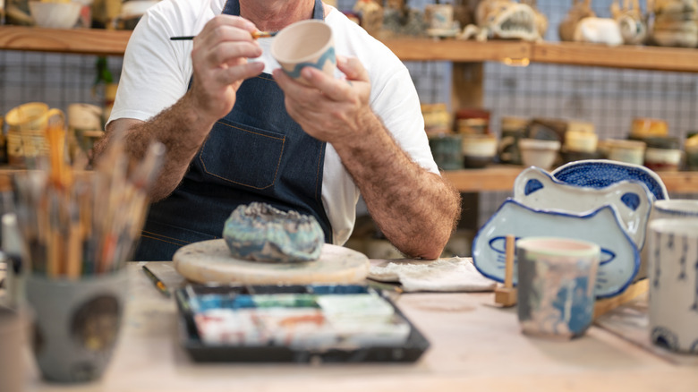 A man painting ceramics in his studio.