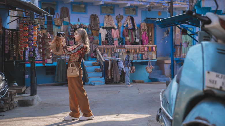 A woman snaps photographs in a marketplace in India