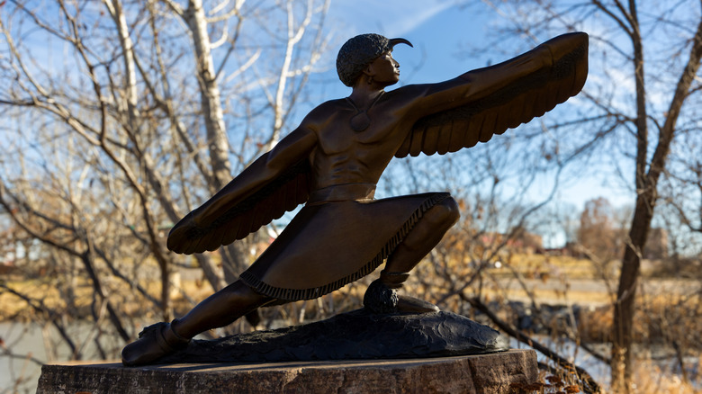 Bronze statue of a winged figure among bare trees