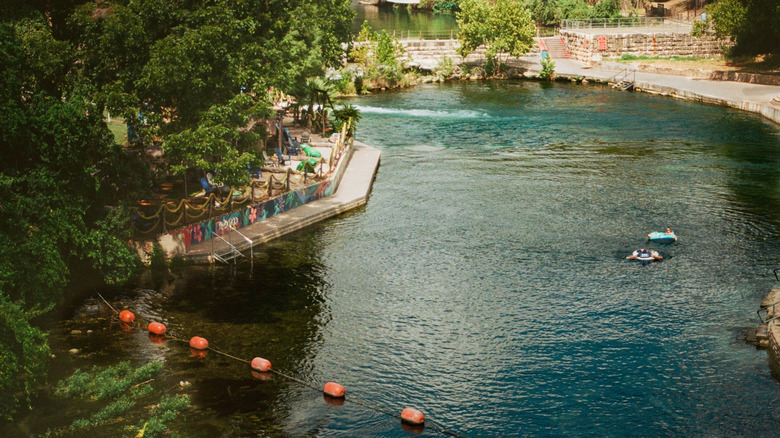A film photograph of the Comal River with two floaters enjoying the river on a lazy afternoon.