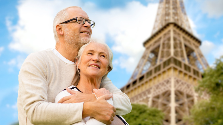 a middle-aged couple smiling in front of the Eiffel Tower