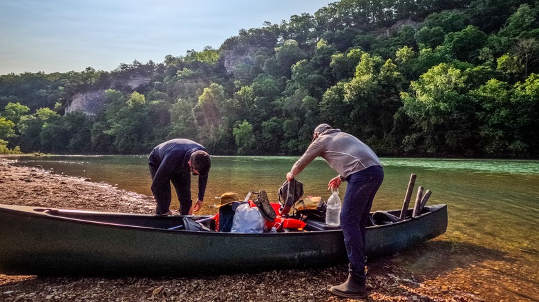 Two men organize equipment in a grounded canoe