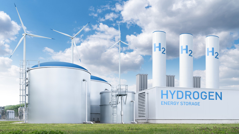 Futuristic-looking image of a hydrogen energy storage facility with windmills in the background.