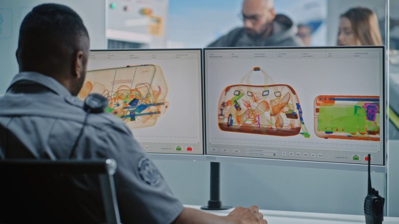 TSA officer looking at bags going through scanners