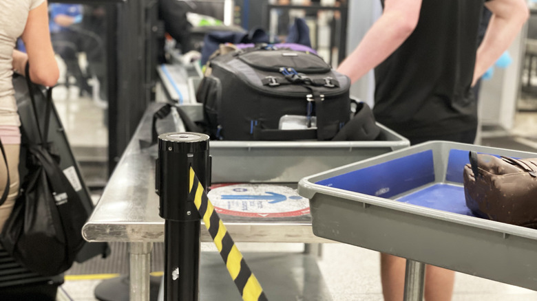 Carry-on luggage moving through TSA in bins