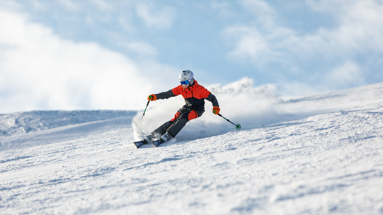 A young man turns while skiing down a snowy run