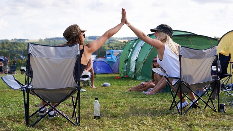 Two women high five at campsite