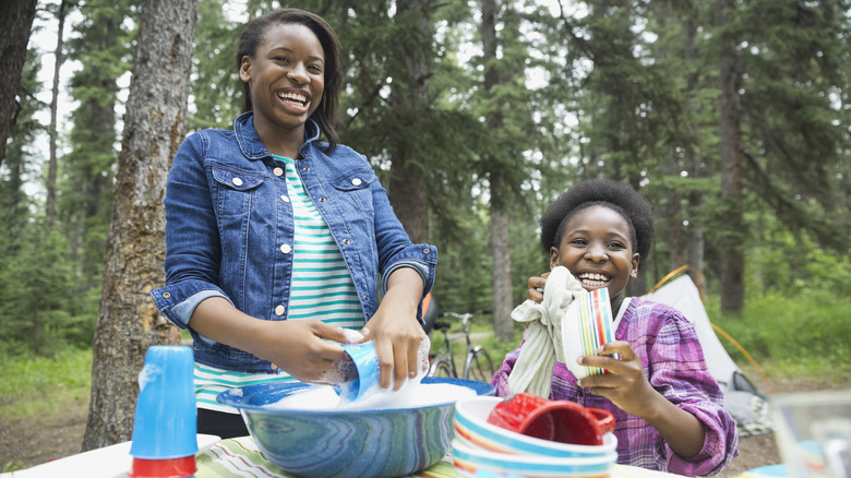 Girls washing dishes outside 