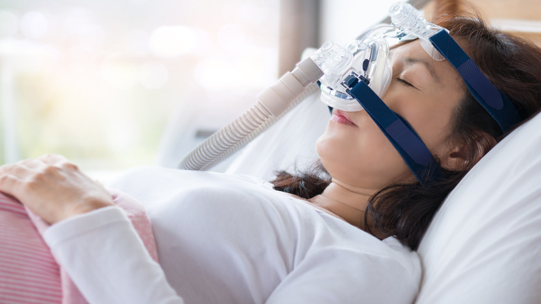 A woman wears a CPAP in bed