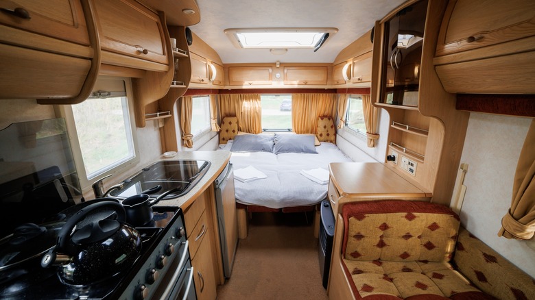 The interior of an RV shows a bed and other amenities