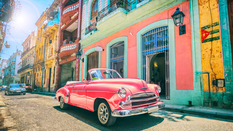 Vintage pink oldtimer car driving through Old Havana Cuba