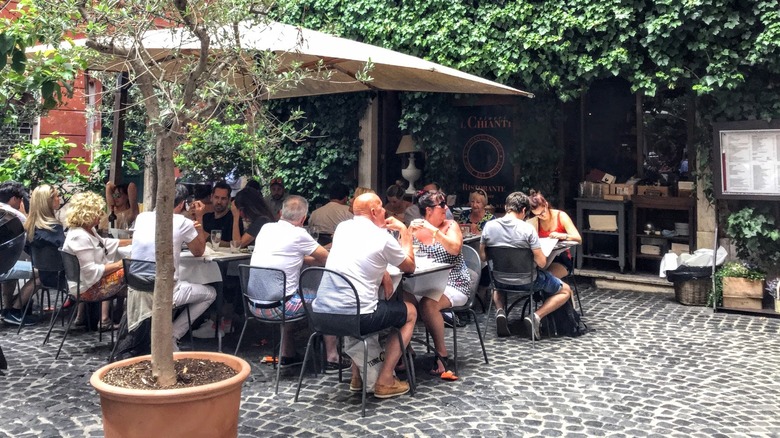 People sitting at an outdoor restaurant terrace surrounded by greenery