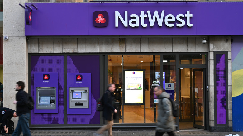 Pedestrians walk past an ATM