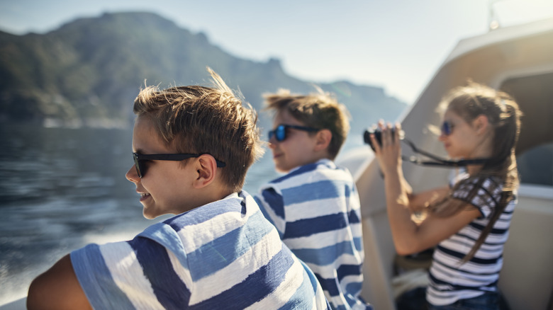 Three youths admire the Amalfi Coast from the deck of a boat