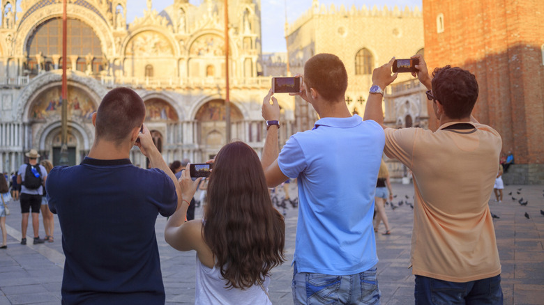 Four tourists taking photos in Italy