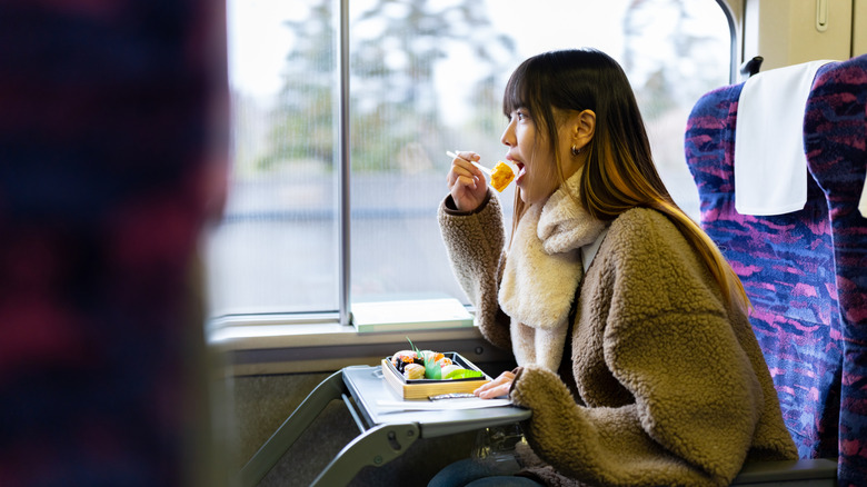 A woman eats from an ekiben on a Japanese train