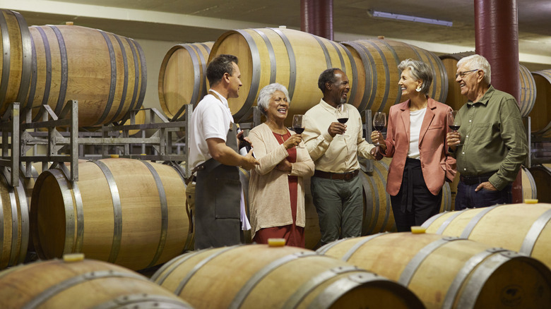 people tasting wine in front of wine barrels