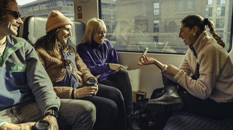 A woman shows a phone to friends on a train