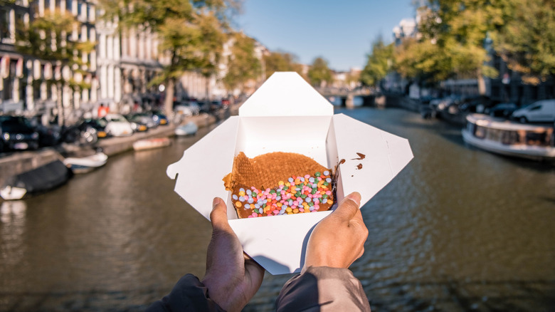 person holding stroopwafel over canal
