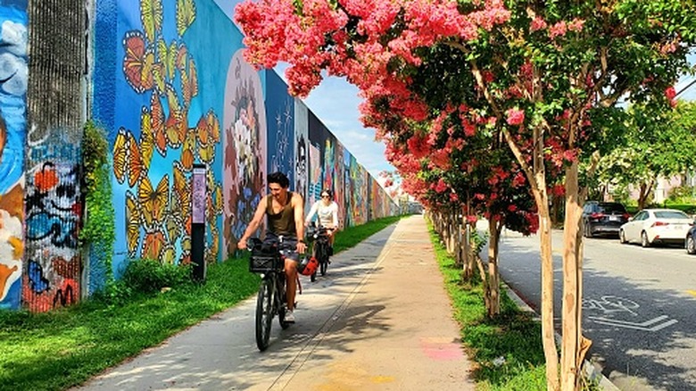 Two cyclists passing by street murals on the Atlanta Beltline.