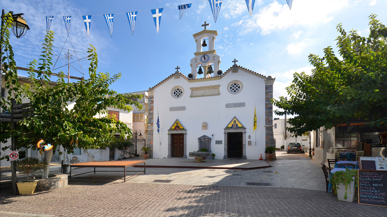 An empty town square with a white church featuring a bell tower