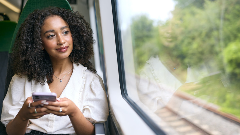A young woman traveling by train looking out of the window.