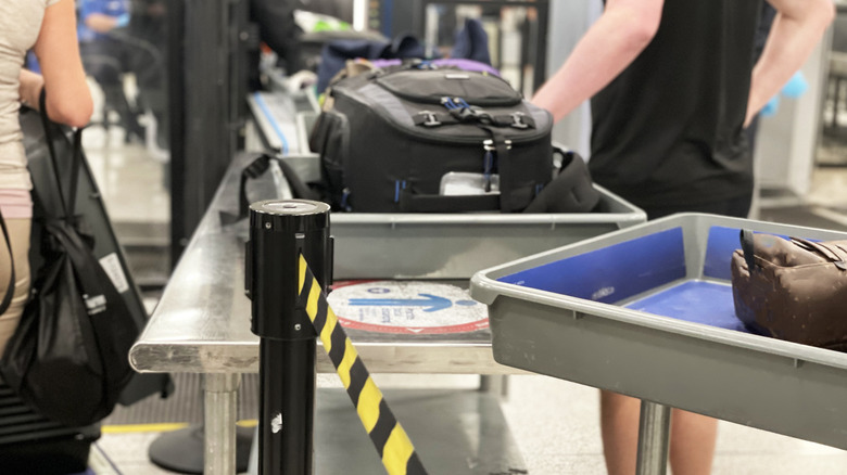 TSA line, shallow bins holding suitcases and bags on a metal table