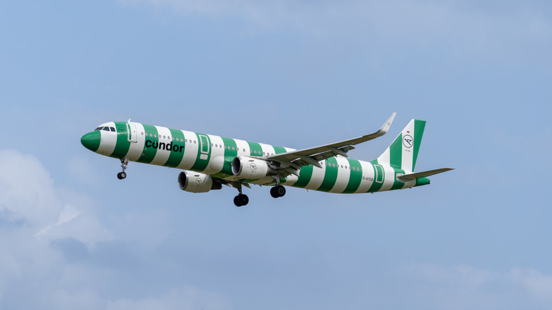 Green and white striped Condor airplane flying in the sky