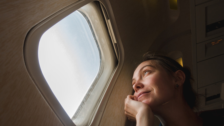 young woman on passenger seat near window in airplane