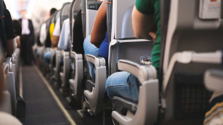 An airplane aisle with passengers in their seats