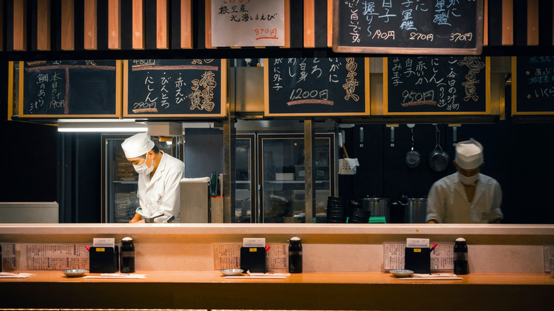 Japanese chefs cooking behind wooden counter