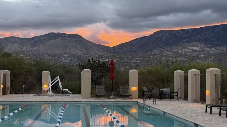A resort pool in front of mountains at sunset.