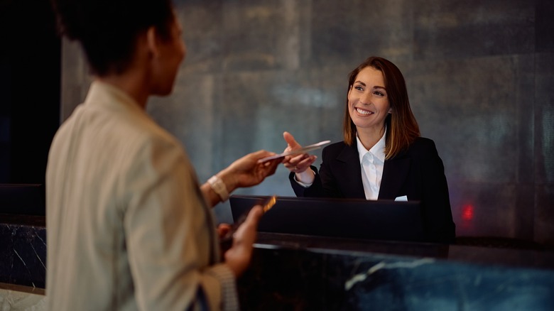 A receptionist welcomes a guest in a hotel lobby