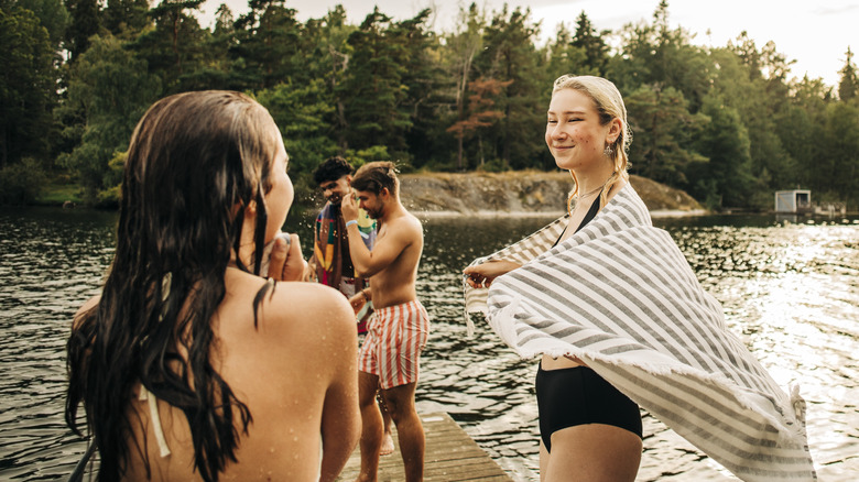 Smiling friends standing on lake dock