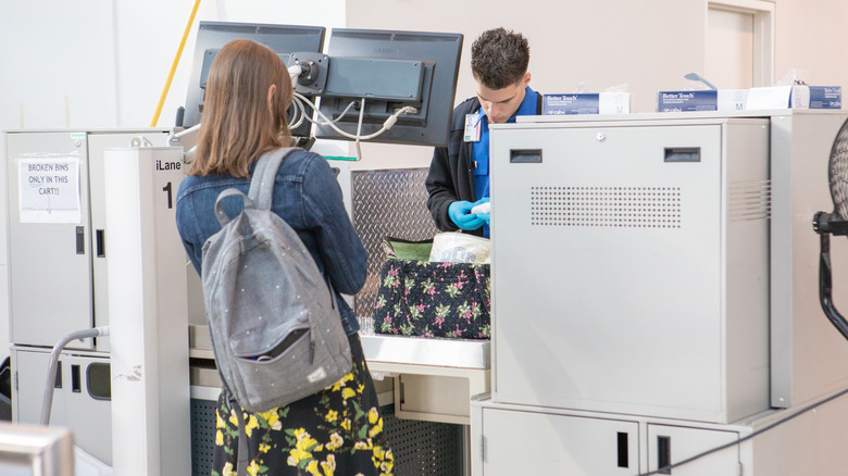 A TSA security agent checking a woman's bag at the airport.