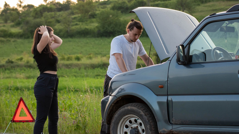 Man and woman on side of road with broken down car
