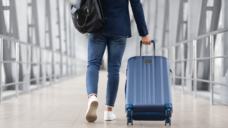 person pulling suitcase through airport