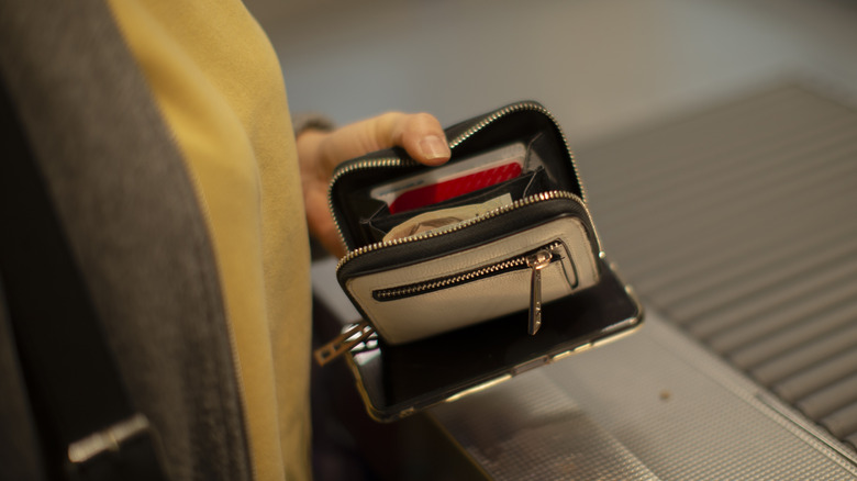 Person holding an open wallet with cash at TSA checkpoint