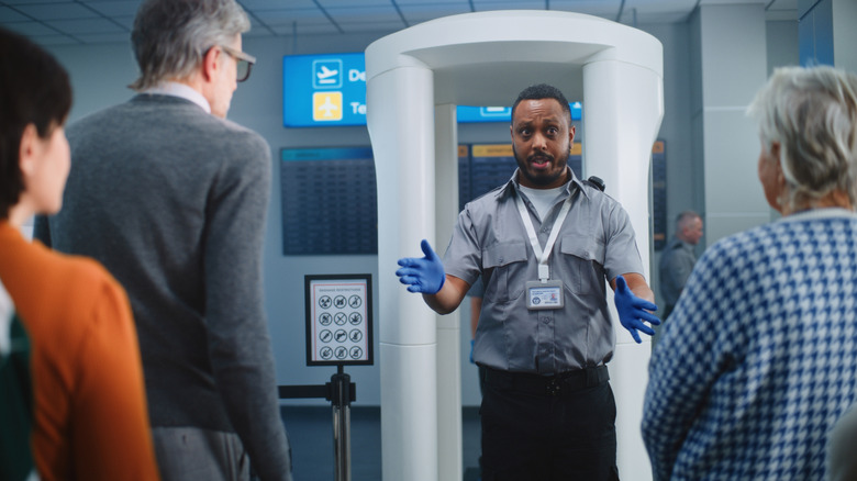An airport security agent directing passengers.