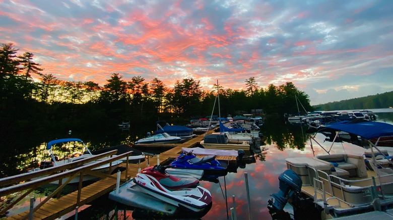 a boat dock at sunset with boats and jet skis
