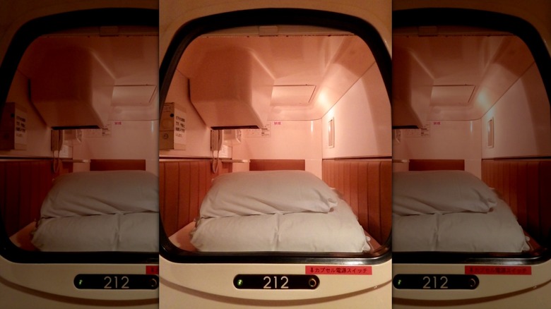 Inside narrow capsule hotel pod light bedding