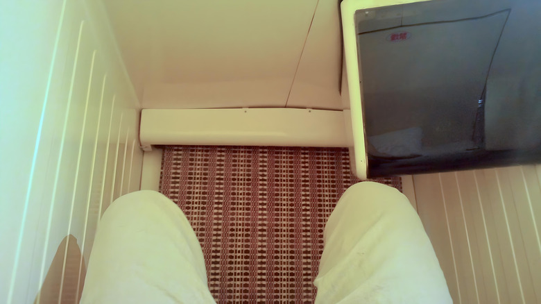Inside capsule hotel pod TV curtain knees